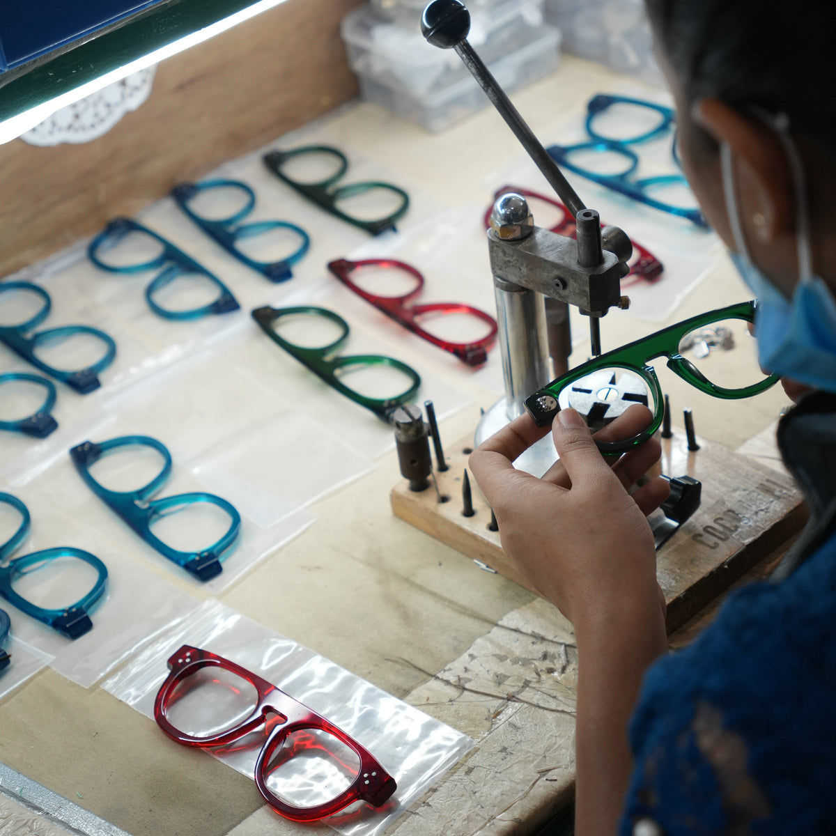 A green frame is held at a workshop bench